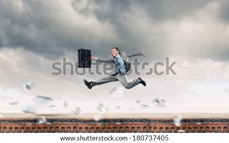 Young cheerful businessman in jump against city background