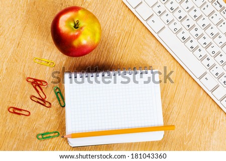 Red apple notepad and keyboard on wooden table