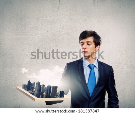 Handsome businessman holding model of modern city