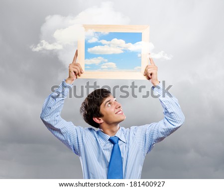 Handsome young man holding frame with pictures