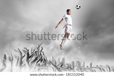 Football player in jump kicking the ball supported by fans