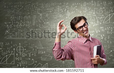 Young funny man in glasses against chalkboard with sketches
