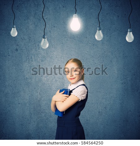 Cute school girl against grey wall with bulbs hanging above