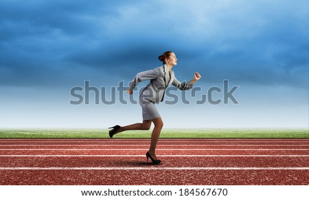 Young businesswoman in suit running on track