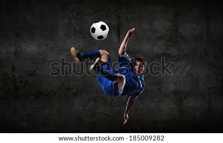 Football player kicking ball against dark background