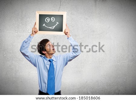 Young happy businessman holding frame with drawn smile