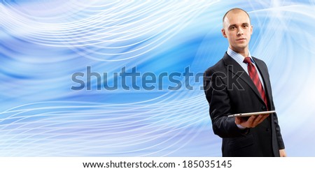 Young businessman holding tablet pc in hand against blue background