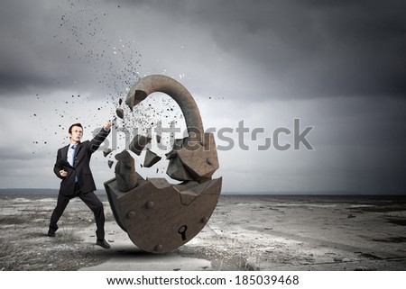 Businessman breaking stone lock with karate kick