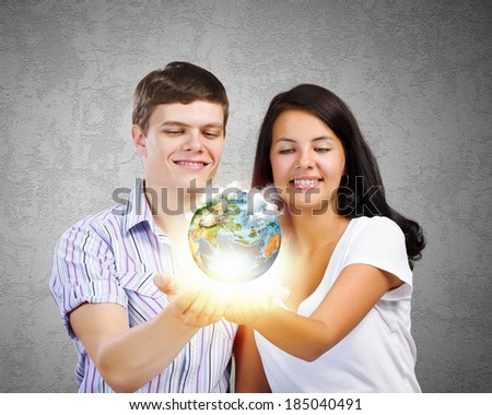 Young happy couple holding earth planet in palms. Elements of this image are furnished by NASA