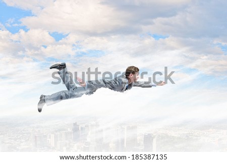 Young businessman superhero flying high in sky