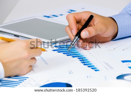 Close up of human hands and documents with graphs and diagrams