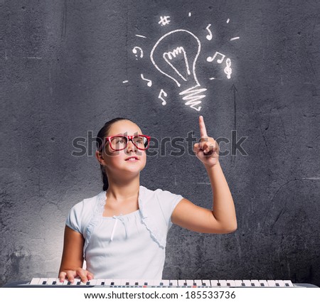 Pretty school girl in funny glasses playing piano