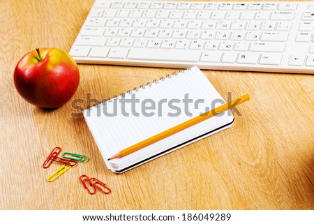 Red apple notepad and keyboard on wooden table
