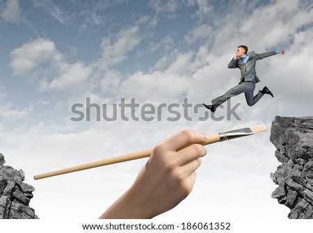 Young businessman in suit jumping over mountain gap