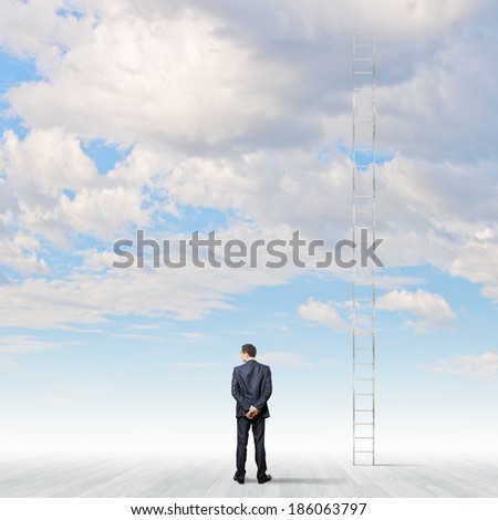Rear view of businessman standing near ladder going high in sky