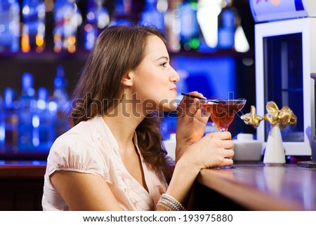 Young pretty girl at bar drinking cocktail