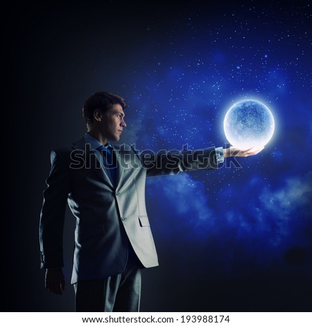 Young businessman holding moon planet in hand