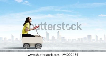 Young funny woman riding in carton box