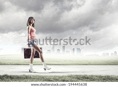 Young pretty woman tourist with suitcase walking on road