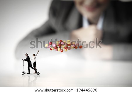 Businessman and businesswoman riding scooter with balloons in hand
