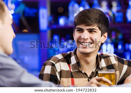 Two young men sitting at bar and talking