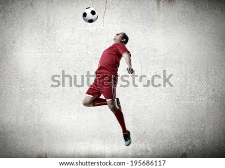 Football player kicking ball against cement background