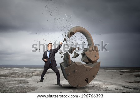 Businessman breaking stone lock with karate kick