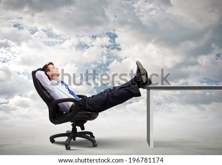 Smiling businessman sitting in chair with legs on table Smiling businessman sitting in chair with legs on table