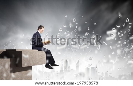 Businessman with book sitting on top of building