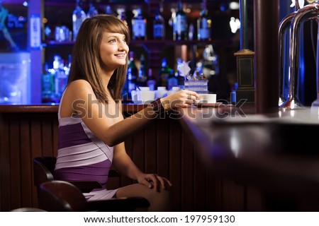 Young pretty lady sitting at bar with cup of coffee