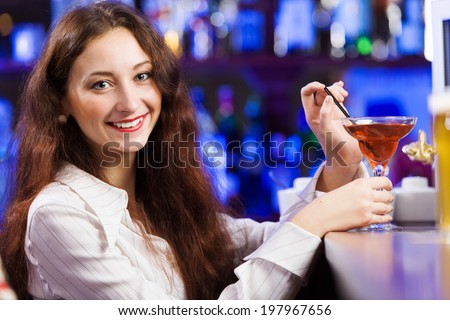 Young pretty girl at bar drinking cocktail