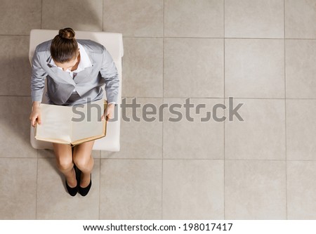 Top view of businesswoman sitting in chair and reading book