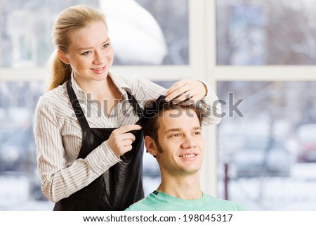 Young man in chair at barbers and woman hairdresser