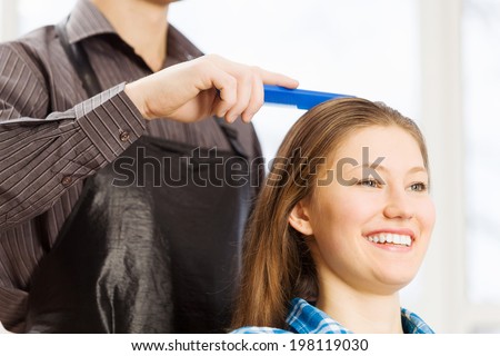 Young woman in chair at barbers and male hairdresser