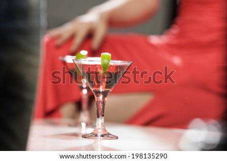Close up of woman in red dress with cocktail in hands