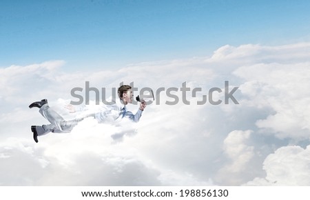 Young businessman with megaphone flying high in sky
