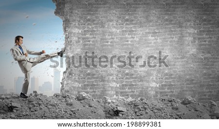 Businessman breaking stone wall with karate kick