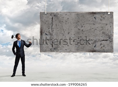Young businessman with hammer in hands and cement banner. Place for text