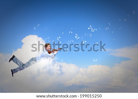 Young businessman flying high above city and playing violin