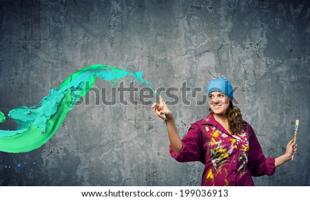 Young woman painter with brush and colorful splashes above