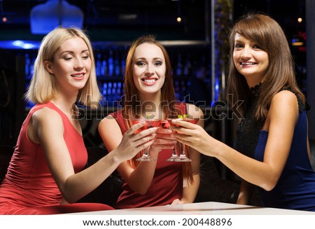Three elegant ladies with cocktails at night club