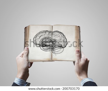 Close up of male hands holding opened book with brain picture