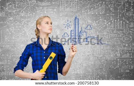 Young woman mechanic with ruler in hand against city background