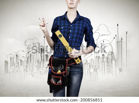 Close up of woman mechanic with ruler in hand against city background