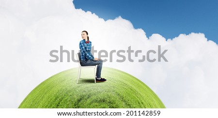 Young troubled woman sitting in chair on green planet
