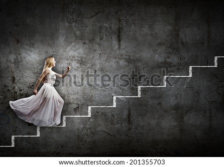 Young woman in white long dress walking up the staircase