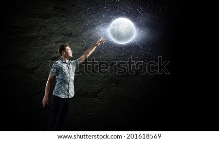 Young man and moon planet against dark background