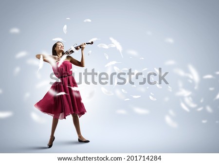 Young attractive woman in red dress playing violin