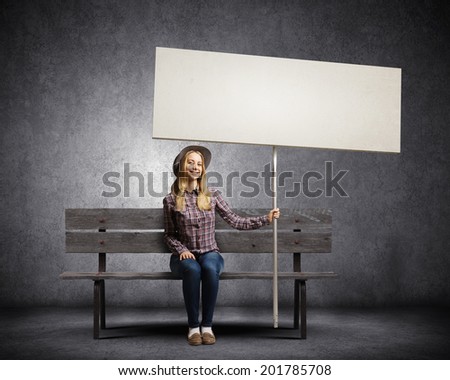 Young woman in casual sitting on bench and holding white blank banner