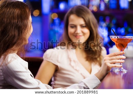Two young pretty women at bar and drinking cocktails